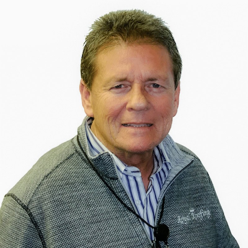 A middle-aged man with short brown hair wearing a gray zip-up sweater over a striped shirt, smiling slightly at the camera against a white background.