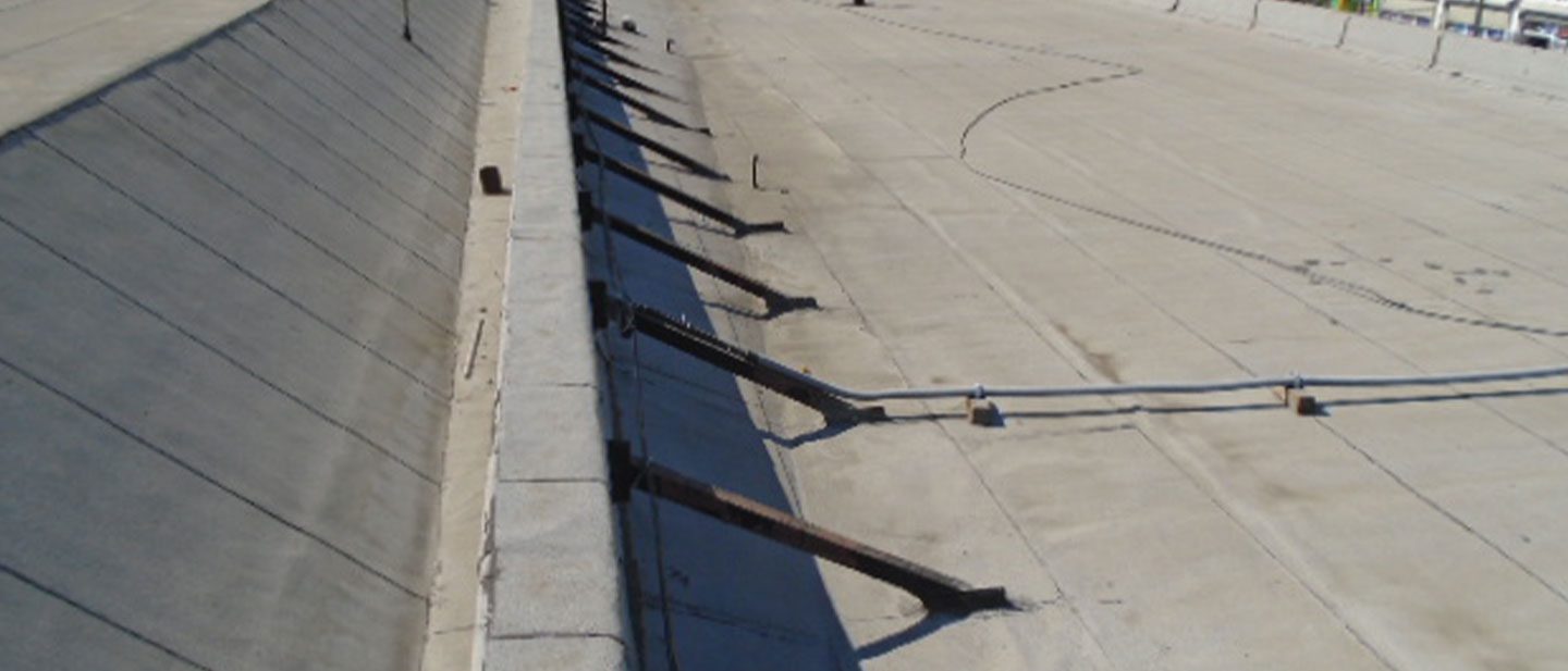 A flat concrete roof with angled metal supports attached along a raised edge, running parallel to the surface. This expansive, sunlit roof showcases the expertise of a CA roofing contractor Orange & Los Angeles County trusts.