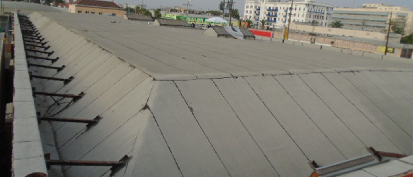 A large, flat, sloped concrete roof structure with support beams on the sides, surrounded by urban buildings and a few trees in the background—ideal for a roofing contractor Orange & Los Angeles County, CA to showcase their expertise.