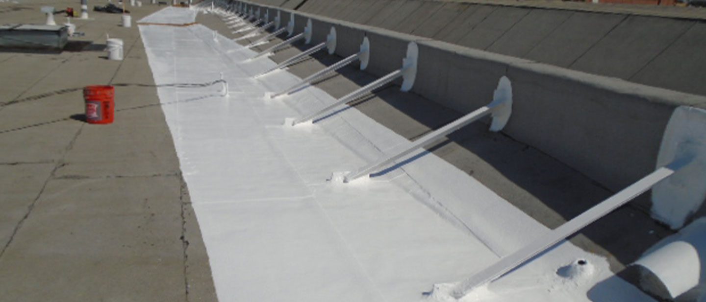 A section of a flat rooftop with support beams painted white, likely as part of a waterproofing or protective coating process by a roofing contractor Orange & Los Angeles County, CA. Buckets and painting equipment are visible in the background.