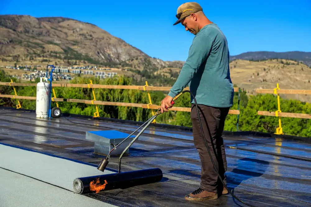 Professional roofing contractor applying roofing membrane on commercial roof in Acton, CA.