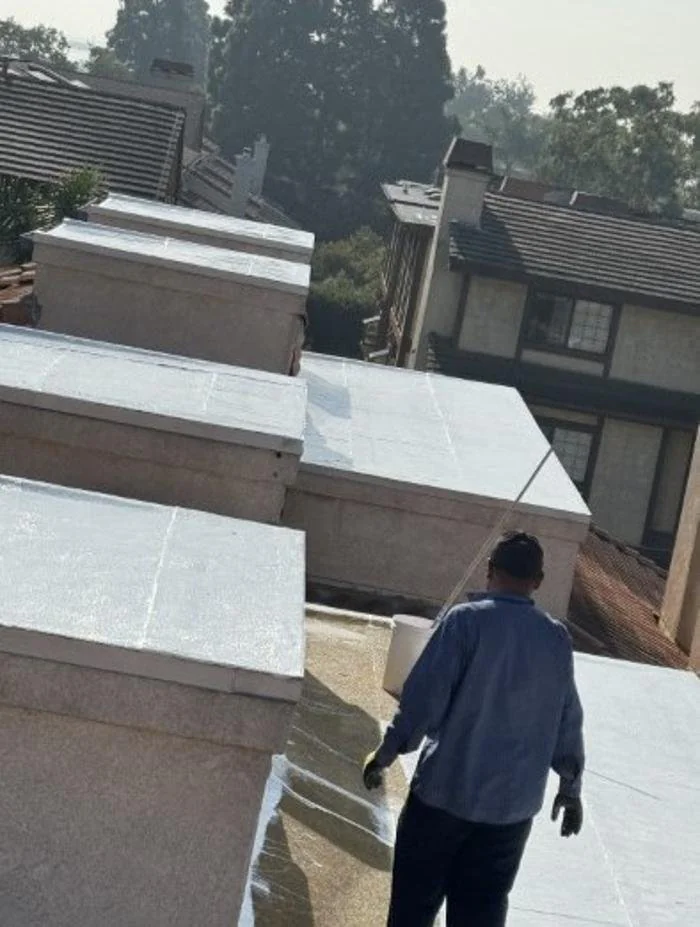 Roofing inspection worker checks shingles and flashing on a residential roof in Los Angeles County, California for damage and wear