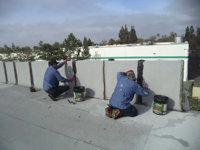 Workers sealing a roof and exterior wall on a Los Angeles County, CA home to help prevent leaks and weather damage