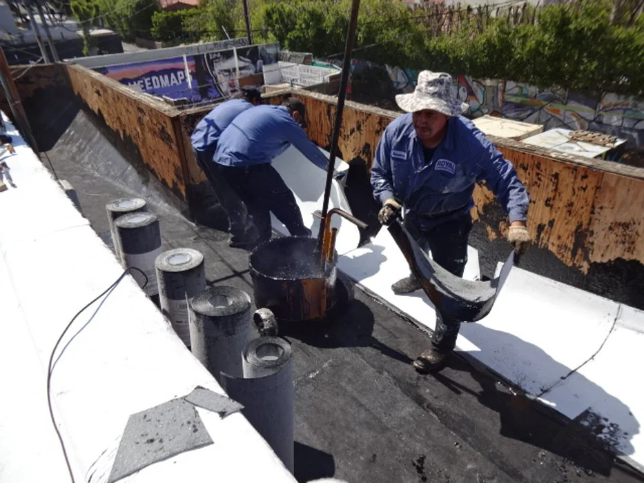 Roofing workers applying roofing materials on a residential roof in Los Angeles County, California