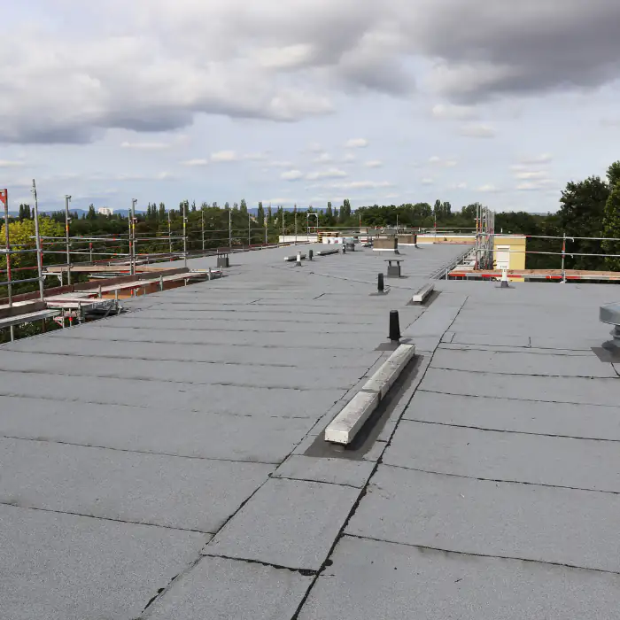 Flat rooftop construction in Orange County, California, with framing, decking, and workers preparing the roof system